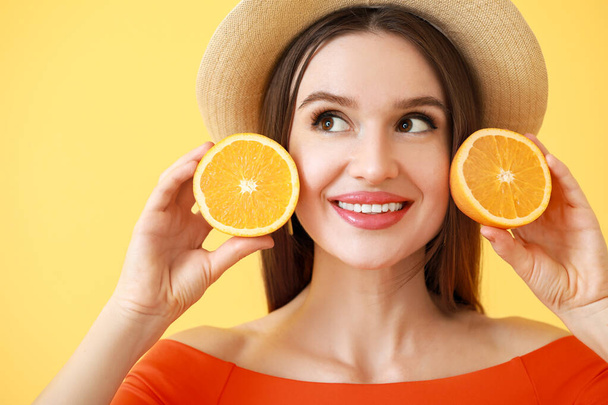 Beautiful young woman with orange slices on color background - Photo, image