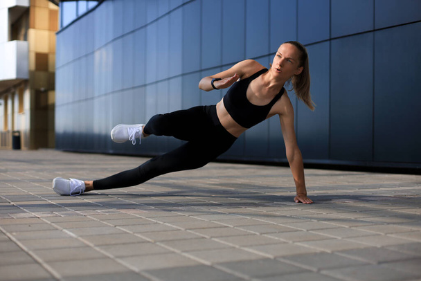 Fitness woman in sportswear doing side plank exercise outdoors - Fotografie, Obrázek