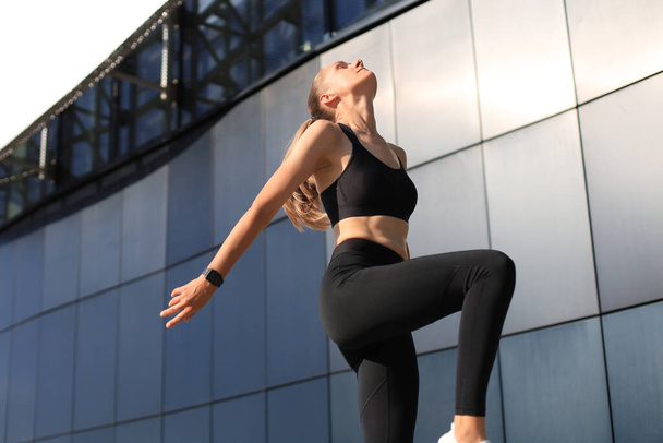 Photo of modern athletic woman in sports clothing jumping while exercising outdoors - Valokuva, kuva