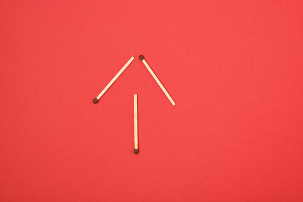 arrow-shaped matches on a red background copy space top view - Фото, зображення