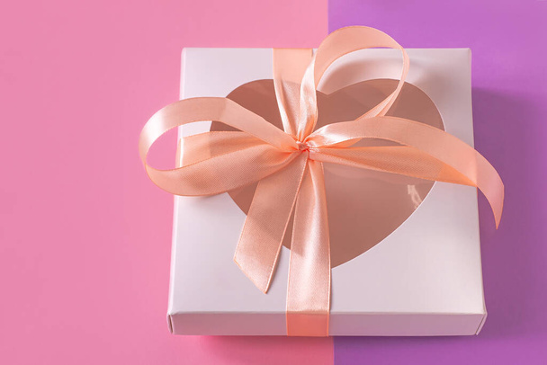 White gift box mockup with heartshaped window on pastel purple pink background flatlay minimal style. Love heart, silk ribbon bow. Valentine's day card template top view copy space social media banner - Photo, Image