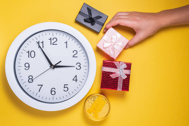 Tiempo de regalo, concepto de compras, reloj y cajas de regalo de Navidad sobre un fondo amarillo. plano laico - Foto, Imagen