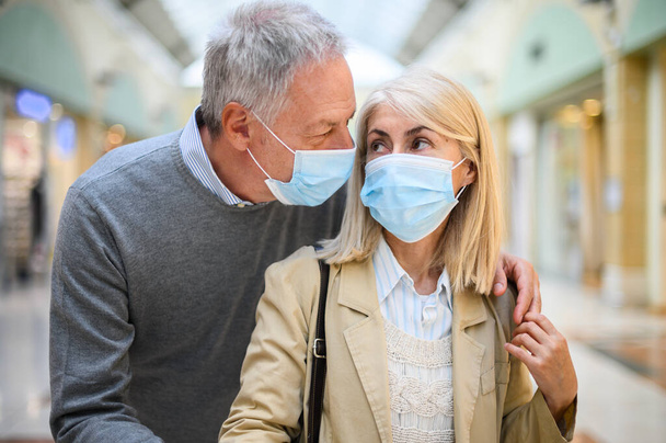 Senior couple shopping in a mall at coronavirus times, wearing masks - Foto, immagini