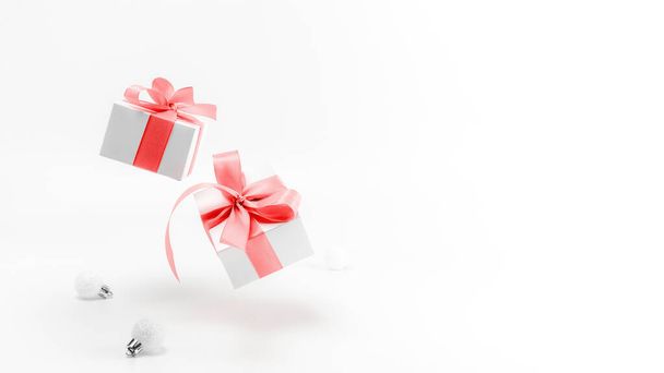 Ornamenti natalizi. Confezione regalo bianca con nastro rosso, palline di Capodanno in composizione natalizia su sfondo bianco per biglietto di auguri. Composizione festiva invernale con spazio copia - Foto, immagini