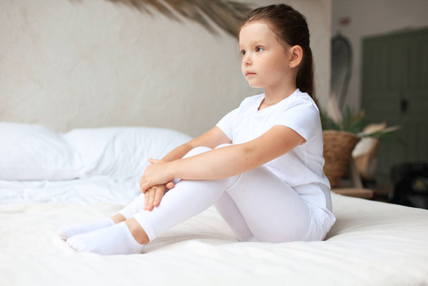 Sweet little girl sitting on her bed at home - Foto, Bild