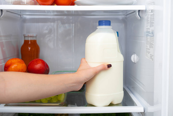 Female hand taking bottle of milk from a fridge - Foto, Imagem