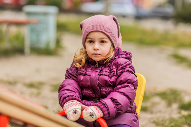 Ragazzina attiva nel parco giochi. Bambina bambina nel parco giochi. Bambino in giacca viola - Foto, immagini