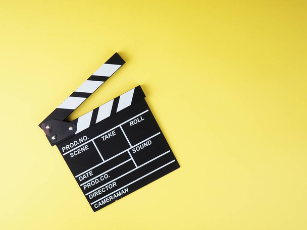 the concept of the film industry, a minimalistic composition on a yellow background with glasses and clapperboard. movies and cinema. - Photo, Image