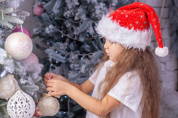 Το πορτραίτο της Πρωτοχρονιάς ενός κοριτσιού, ενός χαριτωμένου παιδιού με καπέλο Αϊ Βασίλη  - Φωτογραφία, εικόνα