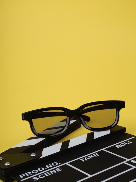 the concept of the film industry, a minimalistic composition on a yellow background with glasses and clapperboard. movies and cinema. - Fotó, kép