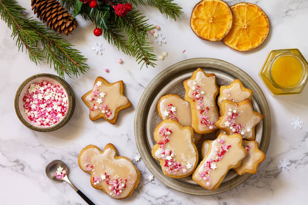 Weihnachtsbacken. Hausgemachte Lebkuchen mit Glasur auf einer Marmorarbeitsplatte. Draufsicht flach gelegt. - Foto, Bild