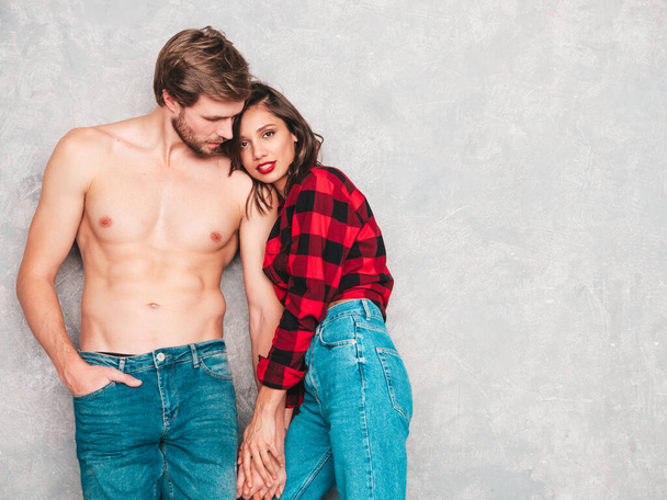 Hot beautiful woman and her handsome boyfriend. Models posing near gray wall in jeans clothes. Young passionate couple hugging before having sex. Sensual pair getting closer for kiss. Lover couple - Foto, Bild