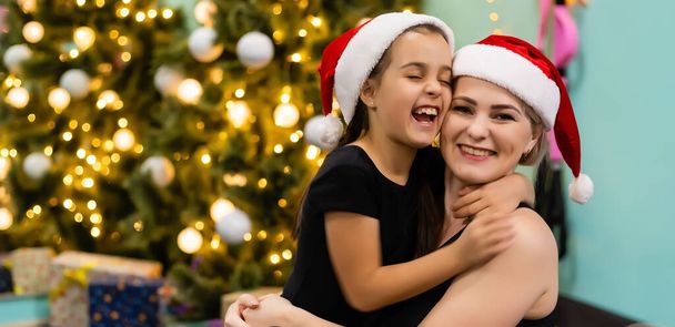 Aimant mère et fille étreignant près de l'arbre de Noël, regardant incroyable. - Photo, image