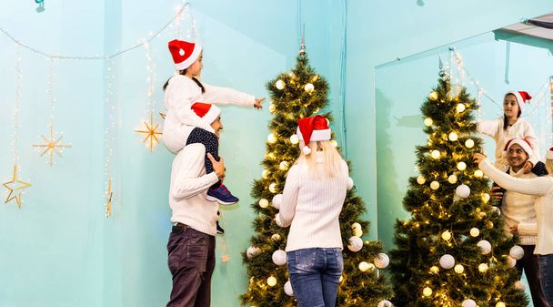 familie, kerst, x-mas, winter, geluk en mensen concept - glimlachende familie in santa helper hoeden met vele geschenkdozen en bengaalse verlichting - Foto, afbeelding