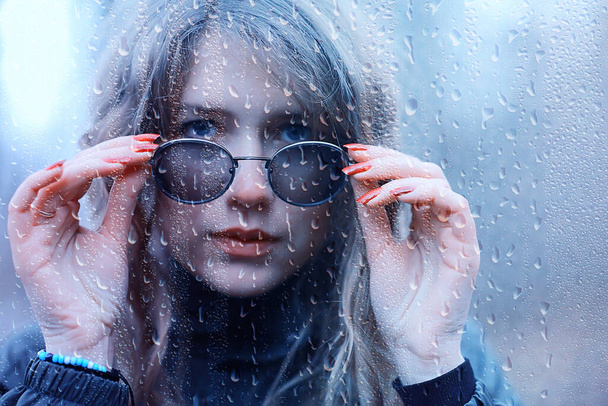 seasonal autumn pornetret, sad girl behind wet glass, raindrops background - Fotó, kép