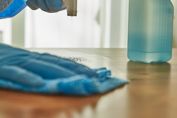 Person disinfecting a table with disinfectant. Cleaning a surface with disinfectant. Coronavirus precaution. - Photo, Image