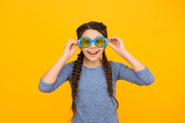 smiling kid girl with stylish braided hair in party glasses on yellow background, fun - Foto, Imagem