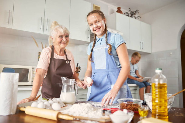 Smiley vnučka tráví čas v kuchyni se starší dámou - Fotografie, Obrázek