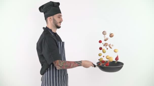 Αρσενικό σεφ πετώντας λαχανικά από γουόκ με λευκό φόντο - Πλάνα, βίντεο