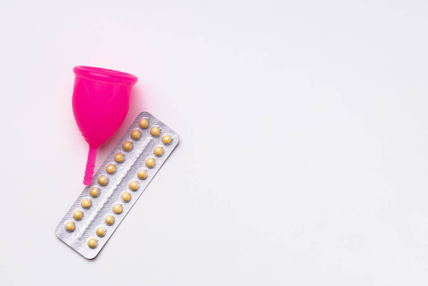 Menstrual cup and oral contraceptive pills top view - Fotó, kép