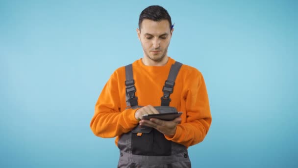 Pracownik w ubraniach przemysłowych rozglądający się i piszący na tabletach - Materiał filmowy, wideo