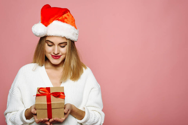 Portrait with copy space, empty place of pretty charming elegant girlfriend celebrating christmas, opening packed gift box isolated on pink background - Zdjęcie, obraz