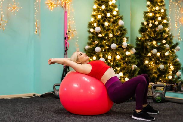 woman goes in for sports near christmas tree at home - Foto, afbeelding