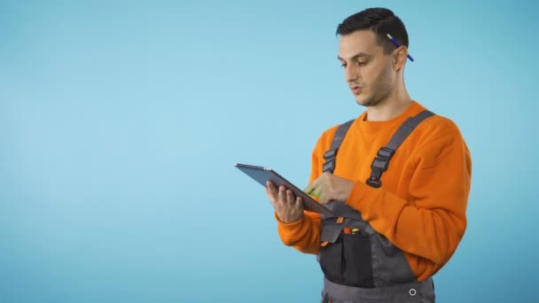 Stavební dělník s perem za uchem si dělá poznámky na tabletu, copyspace - Záběry, video