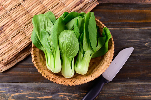 Fresh Bok Choy or Pak Choi (Chinese cabbage) in bamboo basket on wooden background, Organic vegetables, Top view - Photo, Image
