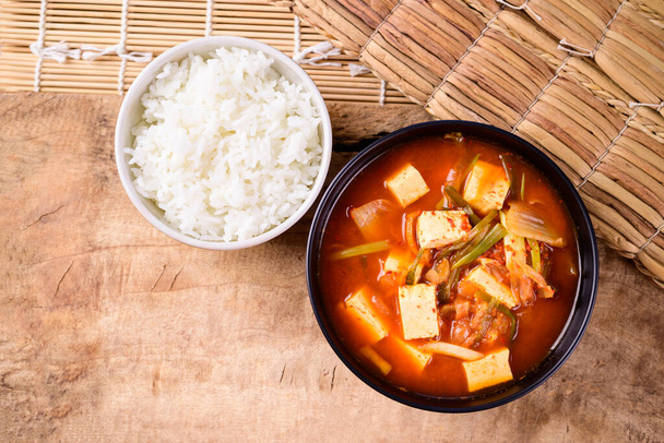 Koreaans eten, Kimchi soep met fofu en gekookte rijst op houten ondergrond - Foto, afbeelding
