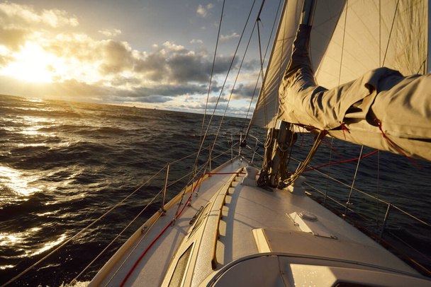 Jacht vitorlázás a nyílt tengeren naplementekor. Közelkép a fedélzetről az orrra, árbocra és vitorlára. Drámai viharos ég, sötét felhők, téli ciklon, viharos időjárás. Óriási látvány. Északi-tenger, Norvégia - Fotó, kép