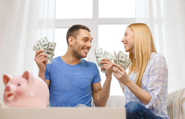 Couple with money and piggybank ot table at home - Photo, Image