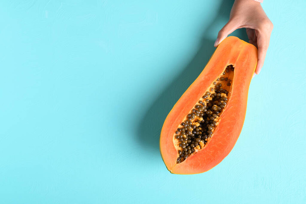 Рука тримає половину стиглих папайї фруктів на пастельному кольоровому фоні, тропічні фрукти, вид зверху
 - Фото, зображення