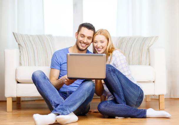 Smiling happy couple with laptop at home - Fotó, kép