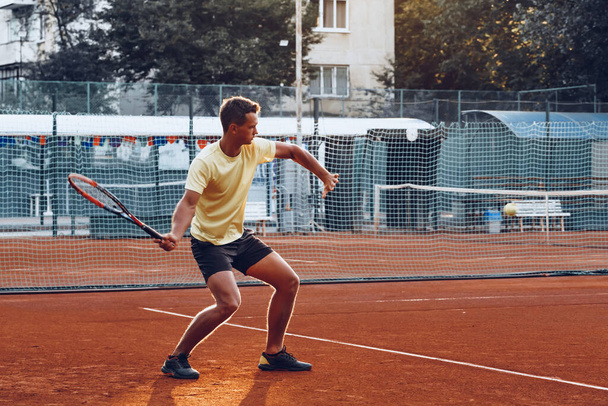 Young handsome man playing tennis on the tennis court - Fotó, kép