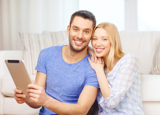 Smiling happy couple with tablet pc at home - 写真・画像