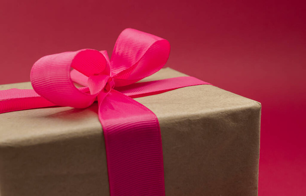 Gift box wrapped in craft paper with ribbon on bright background - Foto, Bild