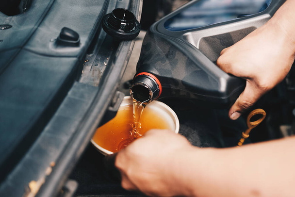 mechanic pouring oil to vehicle engine. serviceman changing motor oil in automobile repair service. maintenance and checkup in car garage - Zdjęcie, obraz