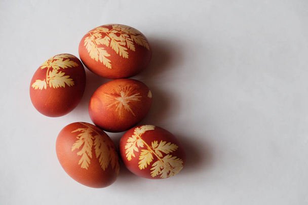 Painted Easter eggs on a white background. Floral pattern on a red eggshell. Festive food. - Foto, Imagen