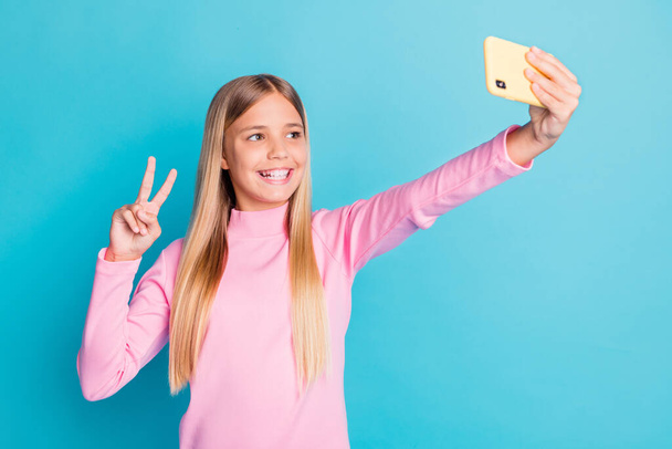 Photo portrait of pretty female preteen taking selfie showing v-sign gesture with two fingers isolated on bright teal color background - Foto, Bild
