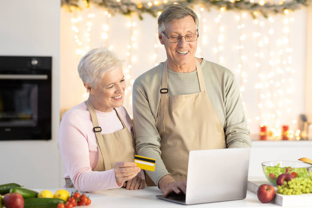 Casal de idosos Compras Usando Laptop e cartão de crédito na cozinha - Foto, Imagem