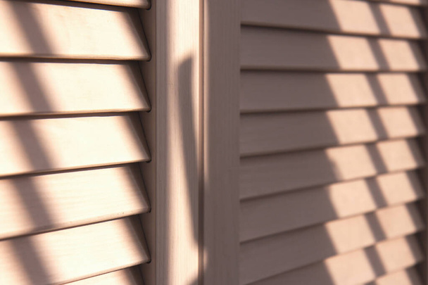 Contrasting shadows on classic white louvered doors. Wooden doors - Fotografie, Obrázek