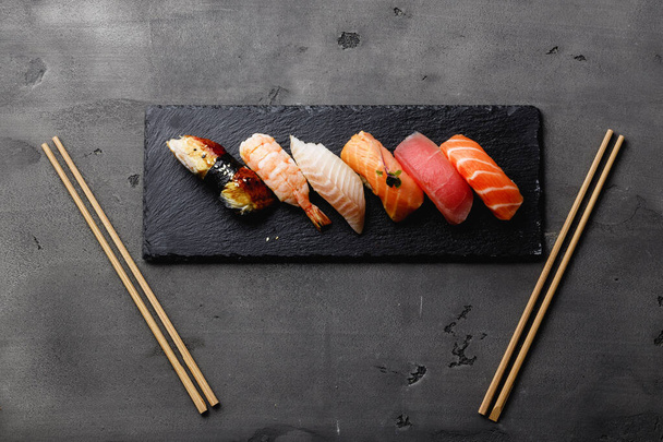 Set of nigiri sushi served on plate on grey background - Photo, image