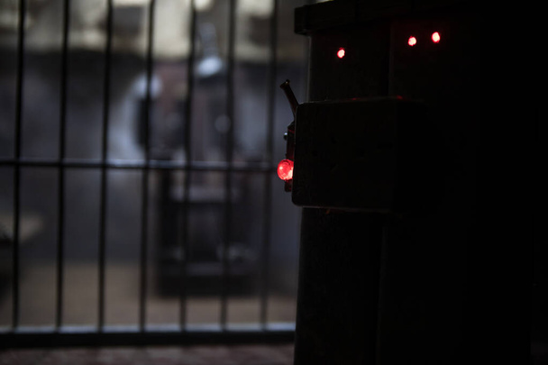 Koncepcja egzekucji. Miniatura krzesła elektrycznego kary śmierci w wybiórczym skupieniu wewnątrz starego więzienia. Stary więzienny zamek. Dekoracja dzieł sztuki. Model skali krzesła elektrycznego w ciemności - Zdjęcie, obraz