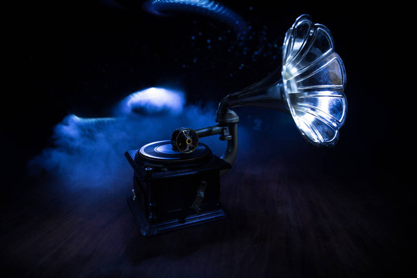 Concept musical. Vieux gramophone sur fond sombre. Gramophone rétro avec disque sur table en bois avec rétroéclairage tonique. Concentration sélective - Photo, image