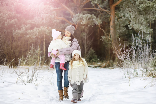 Szczęśliwa rodzina bawi się i śmieje w zimie na świeżym powietrzu w śniegu. Park miejski zimowy dzień - Zdjęcie, obraz