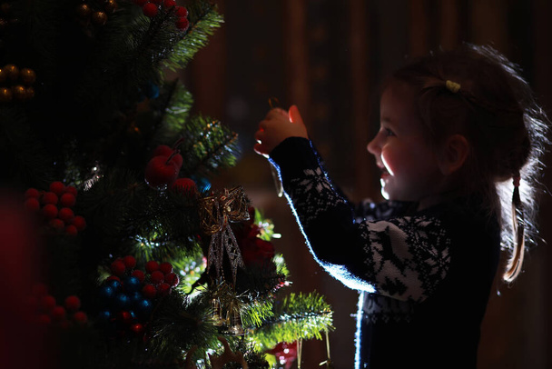 Egy piros kalapos kislány várja a Mikulást. Boldog és fényes karácsonyt. Szép baba, élvezd a karácsonyt. Mikulás lány kicsi gyermek ünnepelni karácsony otthon.  - Fotó, kép