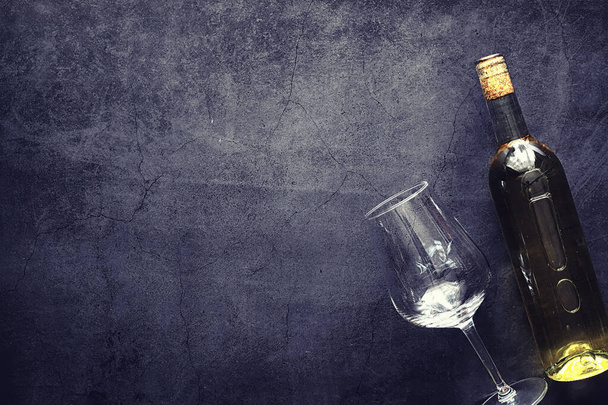 Ένα ποτήρι κόκκινο ξηρό κρασί σε ένα τραπέζι. Σκούρο μπουκάλι και ποτήρι κρασί. - Φωτογραφία, εικόνα