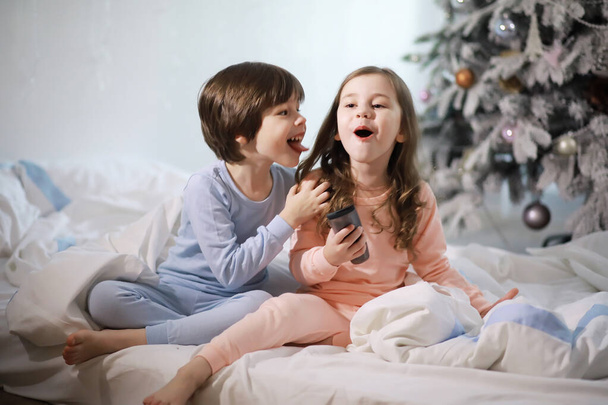 Семья с детьми, веселящимися на кровати под одеялом во время рождественских каникул. - Фото, изображение