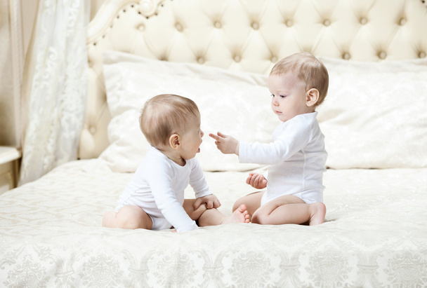 Two baby boys playing on bed - Photo, Image